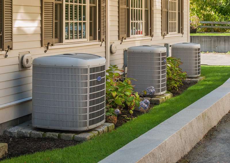 Row of air conditioning condenser units outside a commercial building